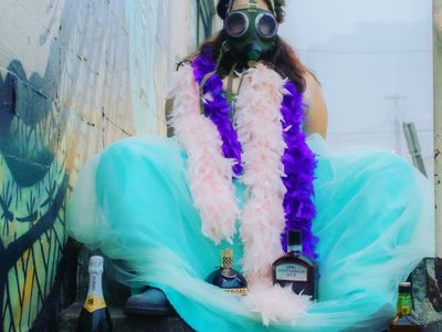Portland Queer Comedy Festival Founder Belinda Carroll, pictured here donning a gas mask and feather boas, will co-host the <a href="https://everout.com/portland-mercury/events/international-coming-out-day-comedy-extravaganza/e36902/">International Coming Out Day Comedy Extravaganza</a> this Sunday on YouTube and XRAY.FM.
